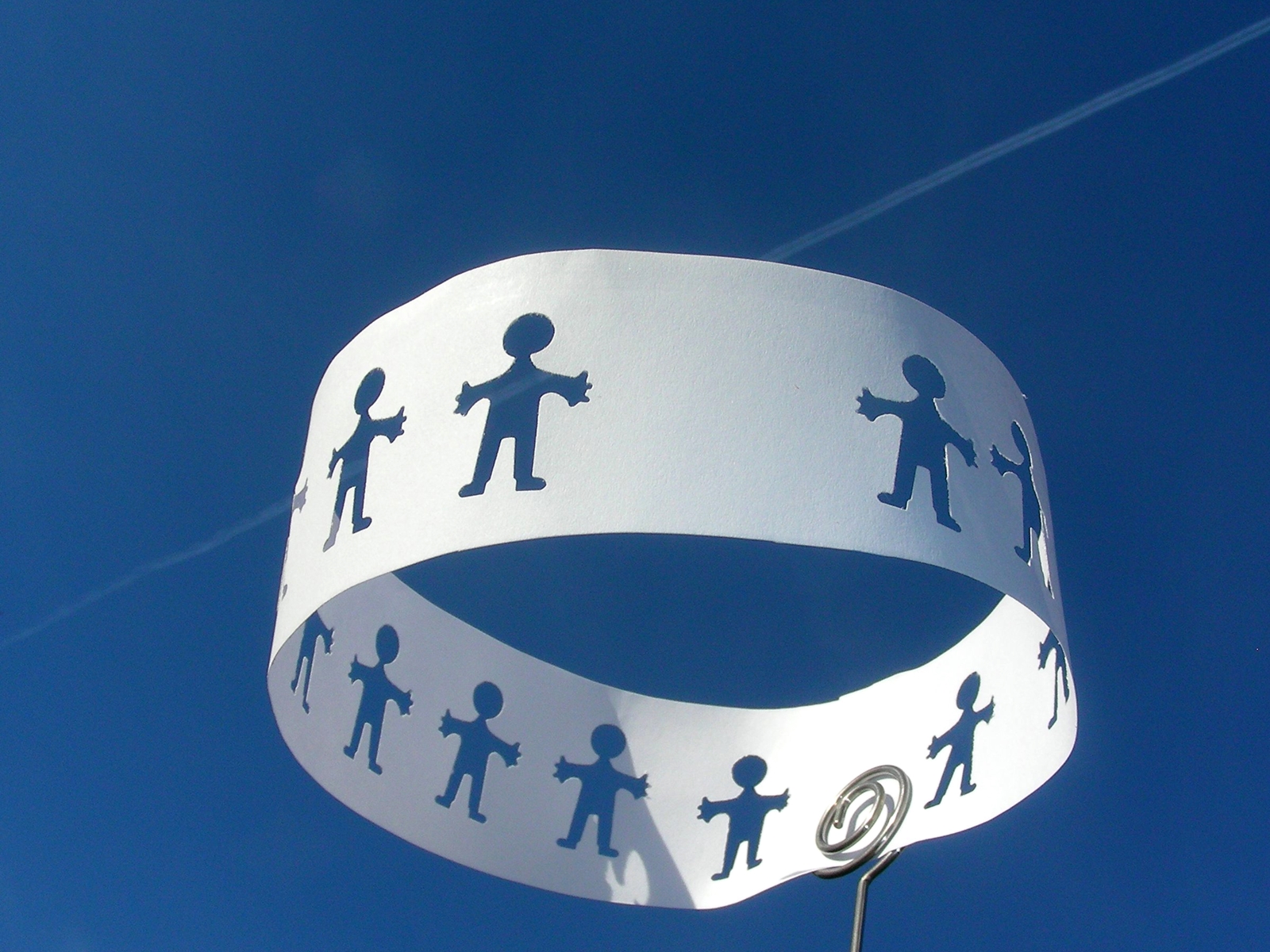 Papierband mit ausgestantzten Figuren vor blauem Himmel