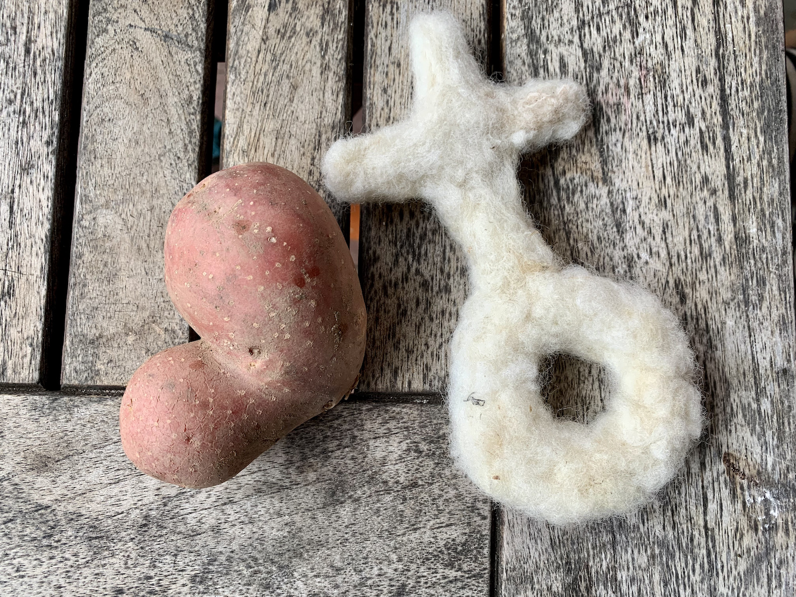 Kugelkreuz aus Wolle und herzförmige Kartoffel