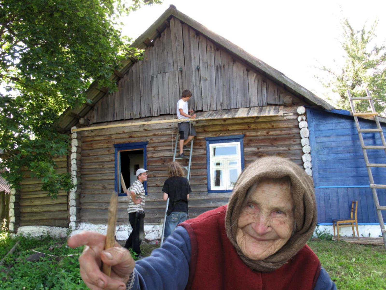 Maria Sinkewitsch vor ihrem Haus mit Teilnehmer*innen des Baueinsatz