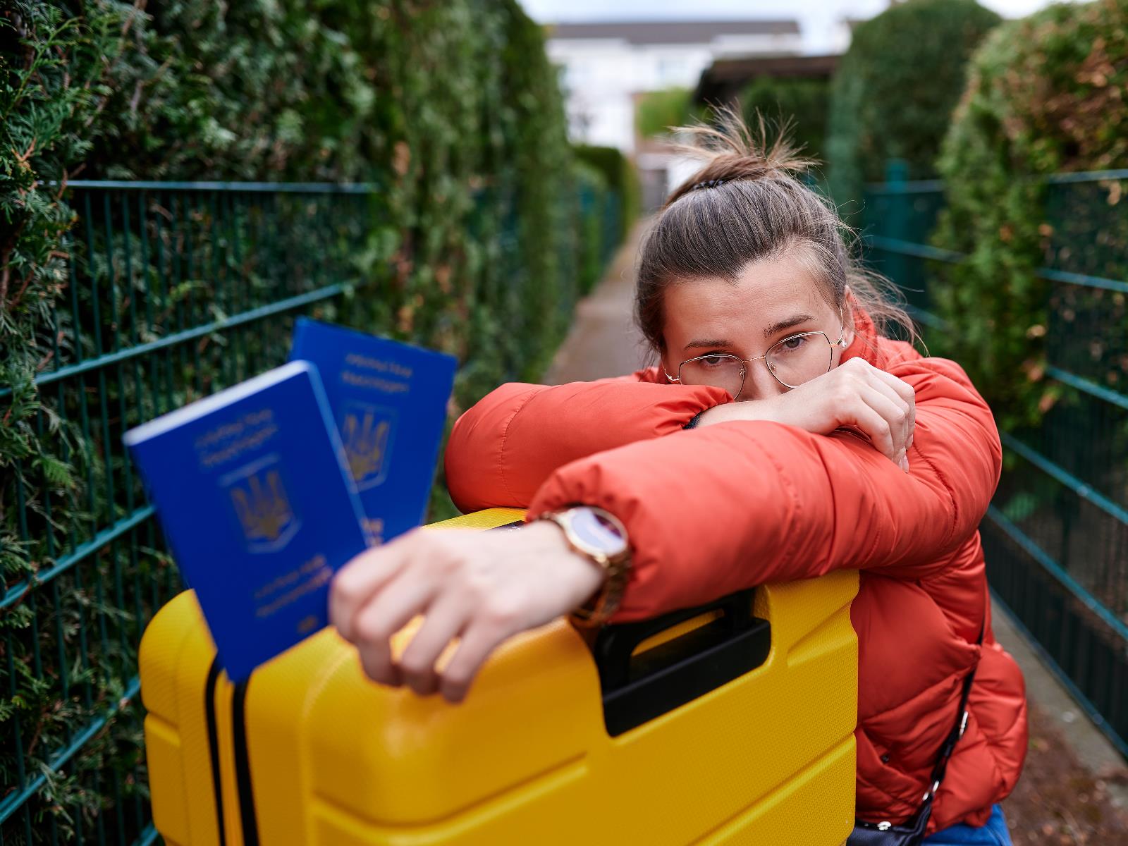 Junge Frau mit einem Koffer und einem ukrainischen Pass in der Hand.