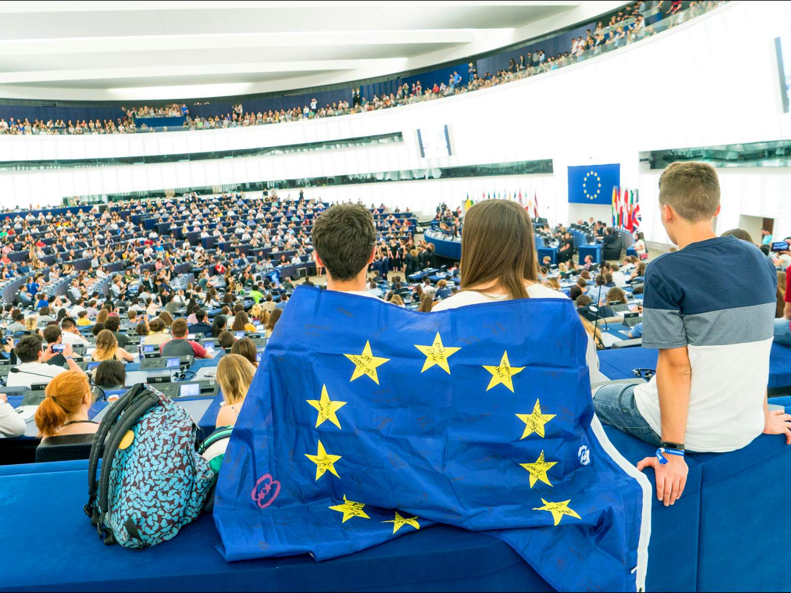 Junge Menschen mit EU-Glagge im EU-Parlament