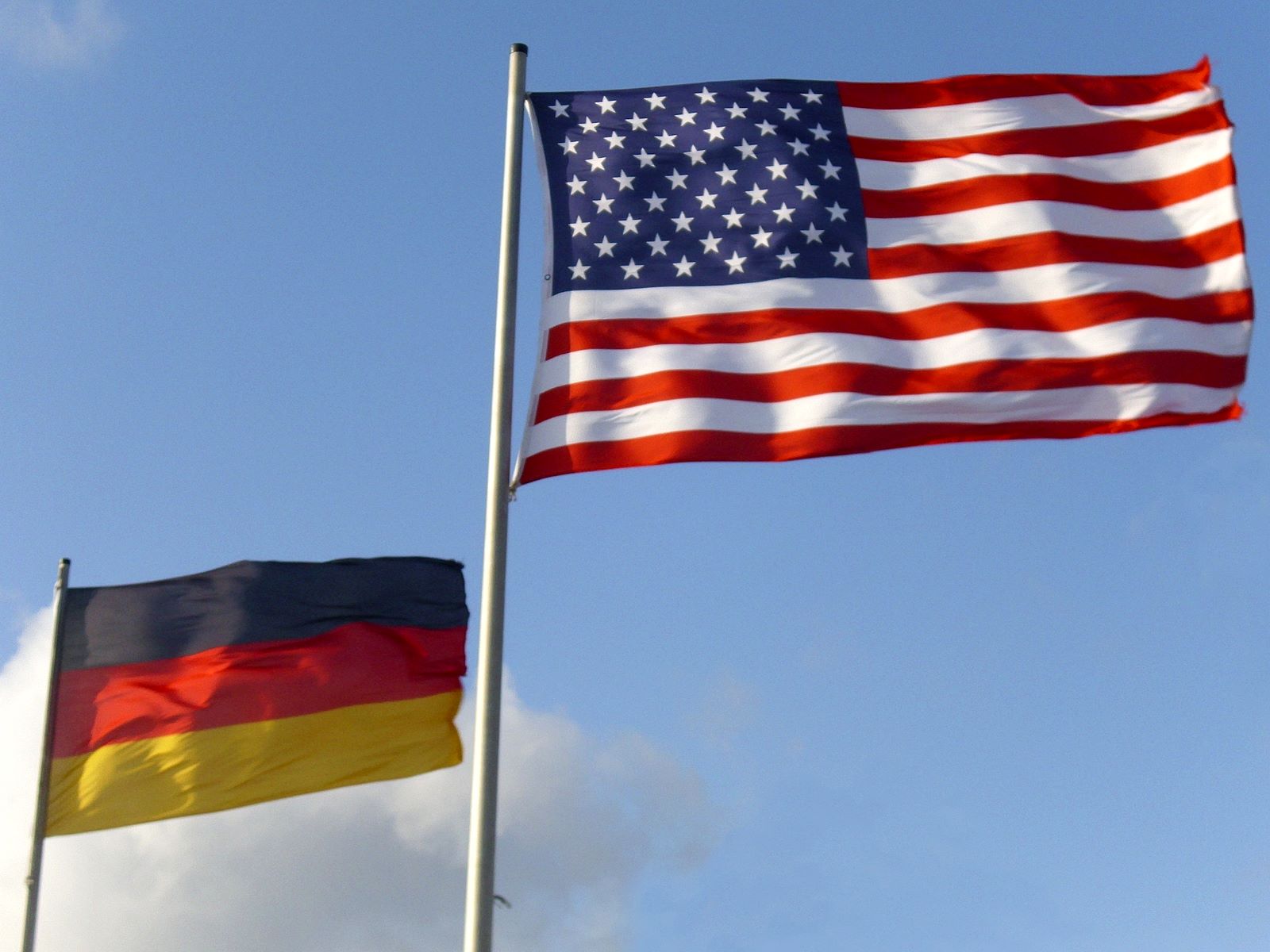 Flaggen von Deutschland und des USA vor blauem Himmel