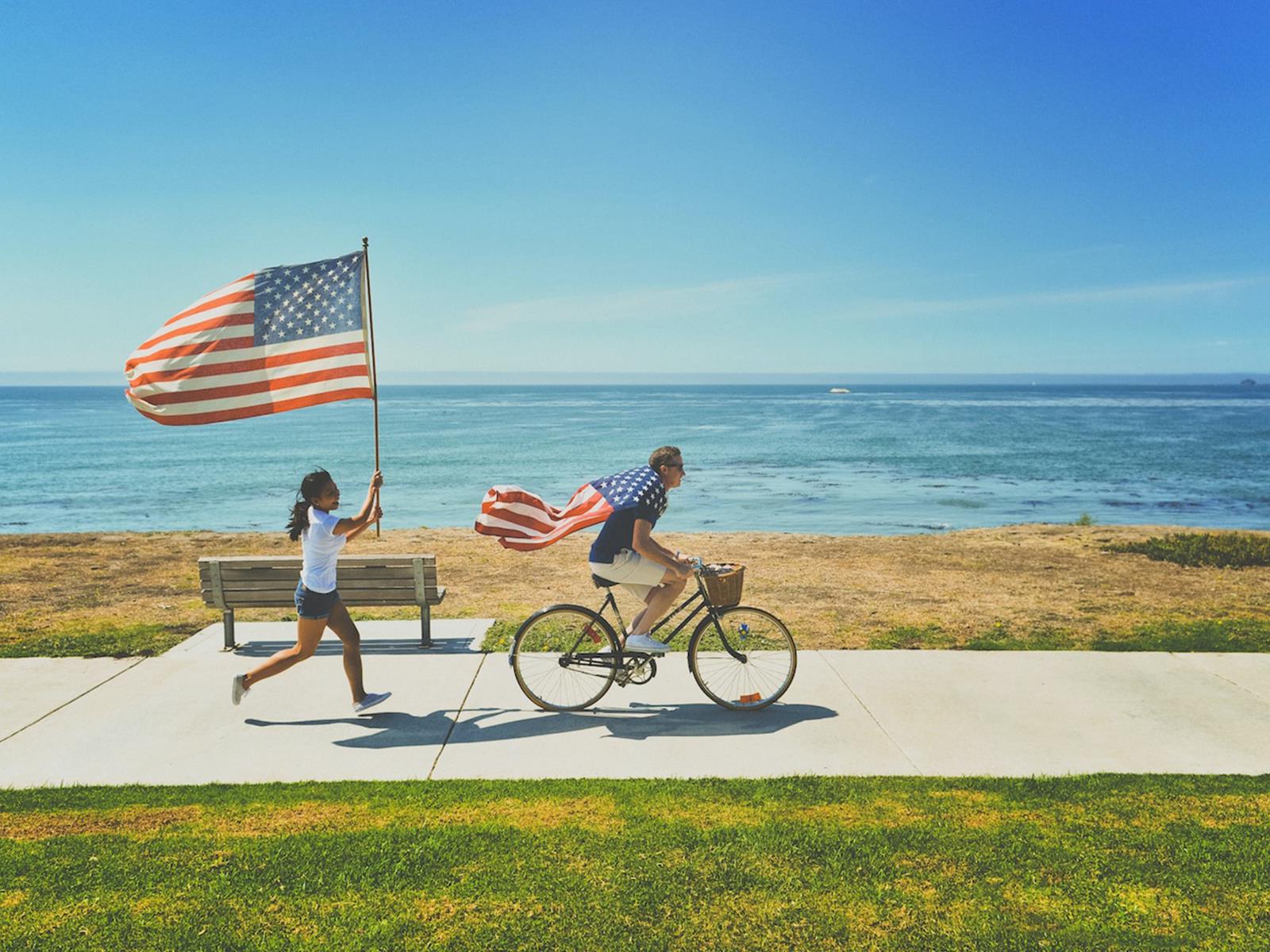 zwei junge Menschen mit USA-Flagge an der Küste.