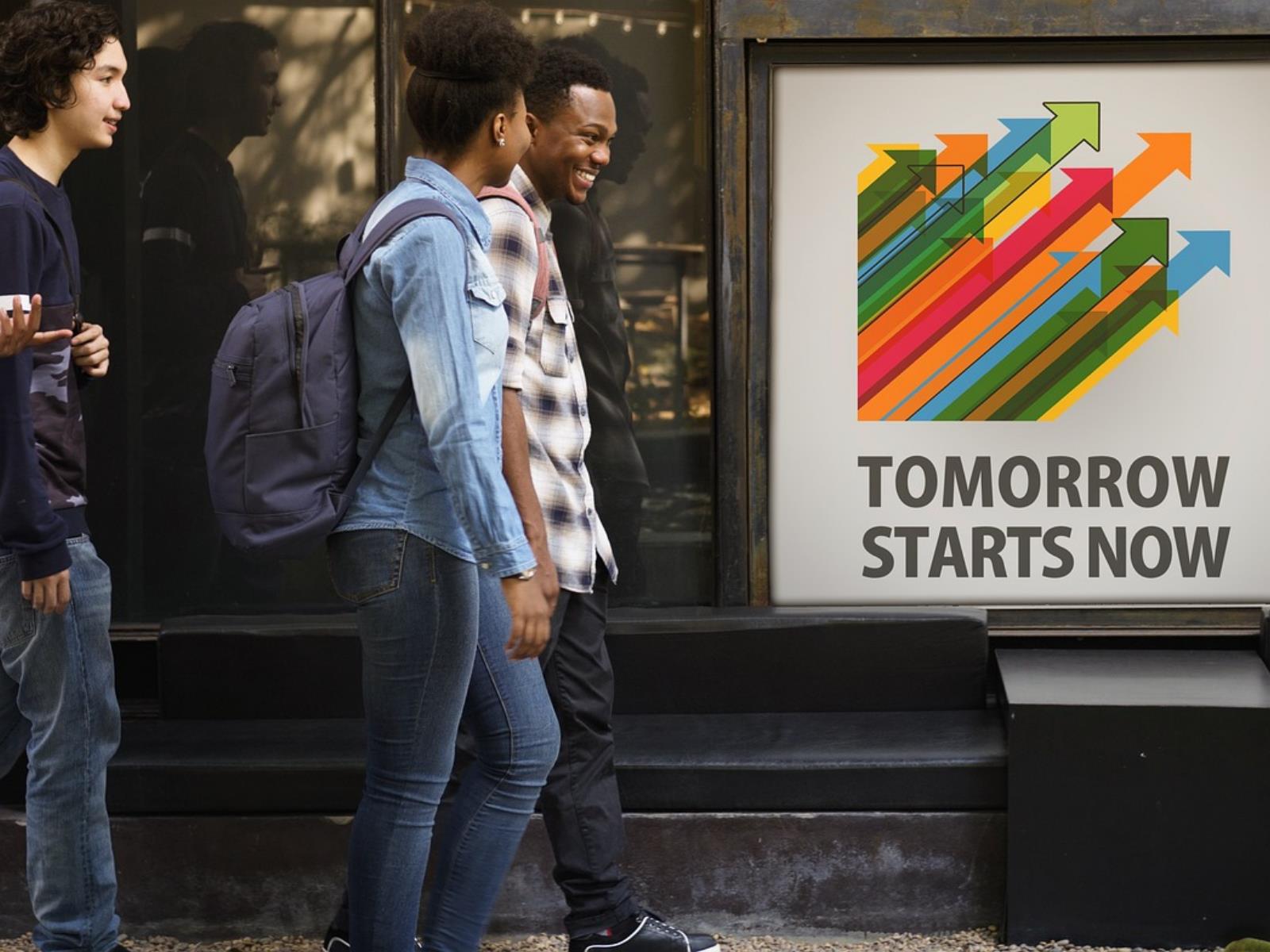 Junge Menschen vor Plakat mit der Aufschrift "Tomorrow starts now"