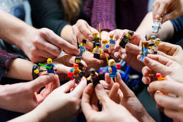 Hände halten Playmobilfiguren, die miteinander "kämpfen"